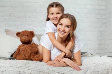 Yatak odası iç karşı poz onu sevimli küçük kızı ile güzel bir annenin Kapalı portre.