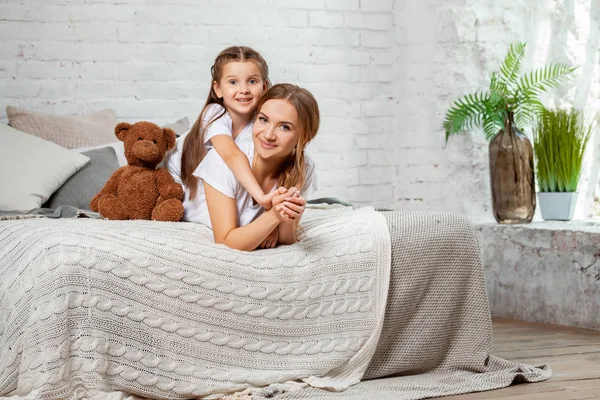 Wewnętrzny portret pięknej matki z jej uroczą małą córką pozującą do wnętrza sypialni. — Zdjęcie stockowe