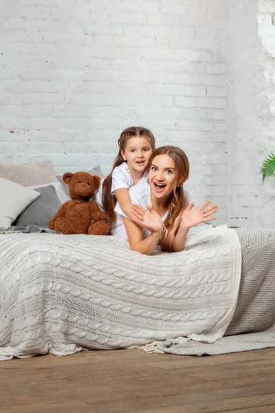 Potret indoor seorang ibu cantik dengan putri kecilnya yang menawan berpose melawan interior kamar tidur . — Stok Foto