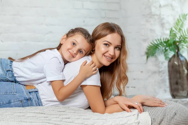 Innenporträt einer schönen Mutter mit ihrer charmanten kleinen Tochter, die vor dem Schlafzimmer posiert. — Stockfoto