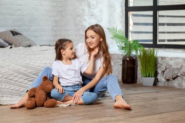 Yatak odası iç karşı poz onu sevimli küçük kızı ile güzel bir annenin Kapalı portre.