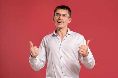 Klasik beyaz gömlekli genç adam pembe arka planda poz veriyor..