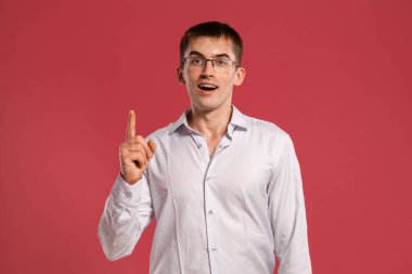 Klasik beyaz gömlekli genç adam pembe arka planda poz veriyor..