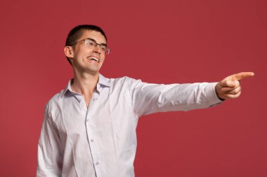 Klasik beyaz gömlekli genç adam pembe arka planda poz veriyor..