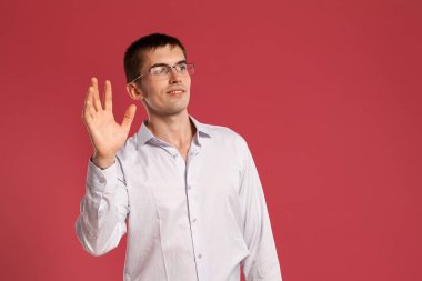 Klasik beyaz gömlekli genç adam pembe arka planda poz veriyor..