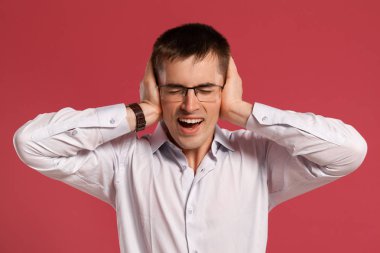 Klasik beyaz gömlekli genç adam pembe arka planda poz veriyor..