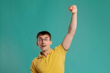 Sarı rahat t-shirt yakışıklı adam mavi bir arka plan üzerinde poz.