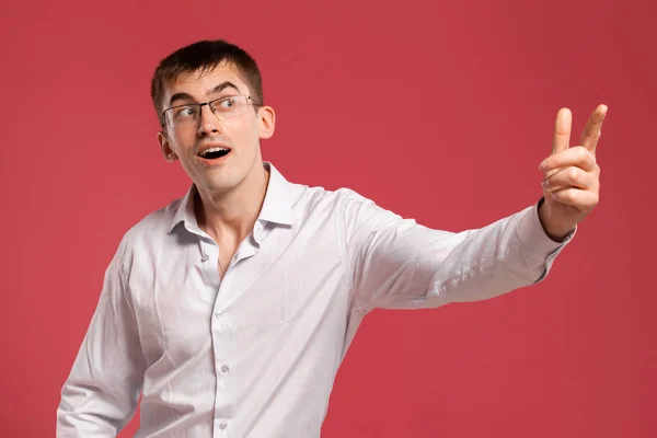 Jovem em uma camisa branca clássica está posando sobre um fundo rosa . — Fotografia de Stock