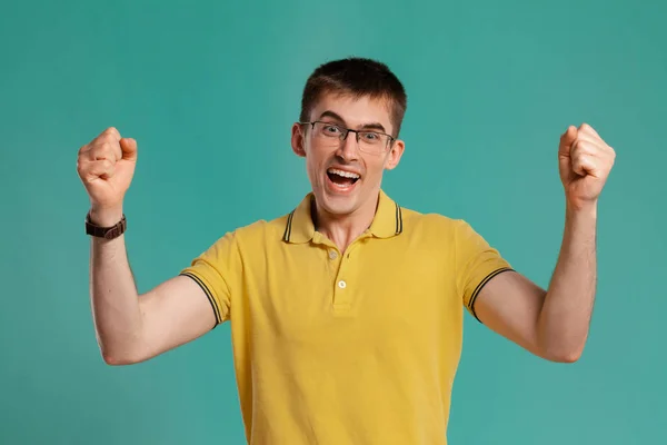 Chico guapo con una camiseta casual amarilla posando sobre un fondo azul . —  Fotos de Stock