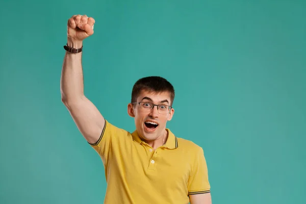 Chico guapo con una camiseta casual amarilla posando sobre un fondo azul . —  Fotos de Stock