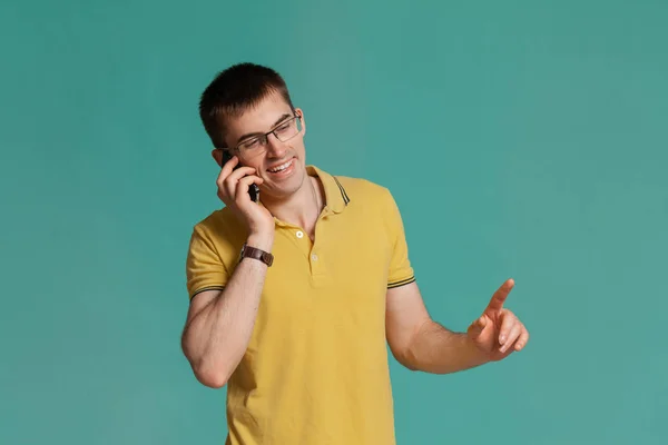 Chico guapo con una camiseta casual amarilla posando sobre un fondo azul . —  Fotos de Stock