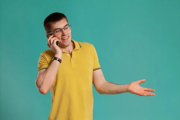 Chico guapo con una camiseta casual amarilla posando sobre un fondo azul . —  Fotos de Stock