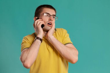 Sarı rahat t-shirt yakışıklı adam mavi bir arka plan üzerinde poz.