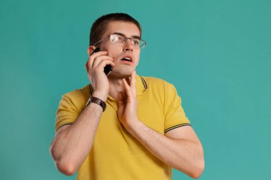 Sarı rahat t-shirt yakışıklı adam mavi bir arka plan üzerinde poz.