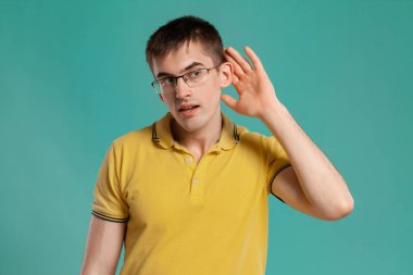 Sarı rahat t-shirt yakışıklı adam mavi bir arka plan üzerinde poz.