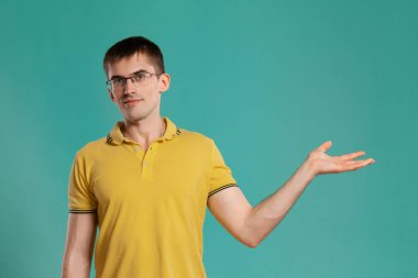 Sarı rahat t-shirt yakışıklı adam mavi bir arka plan üzerinde poz.