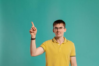 Sarı rahat t-shirt yakışıklı adam mavi bir arka plan üzerinde poz.