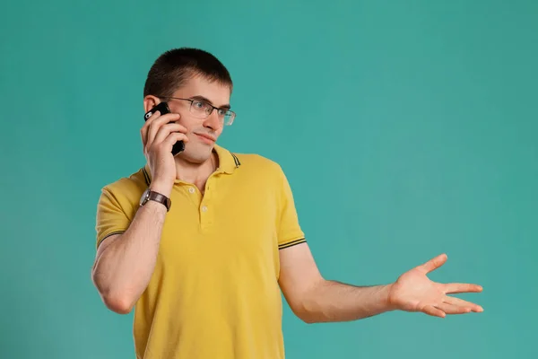 Chico guapo con una camiseta casual amarilla posando sobre un fondo azul . —  Fotos de Stock