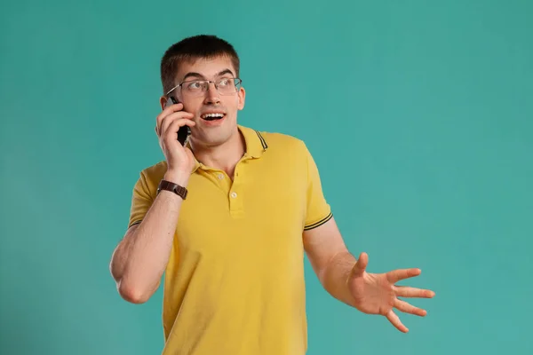 Schöner Kerl in einem gelben lässigen T-Shirt posiert vor blauem Hintergrund. — Stockfoto