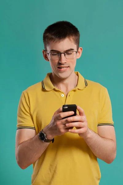 Chico guapo con una camiseta casual amarilla posando sobre un fondo azul . —  Fotos de Stock