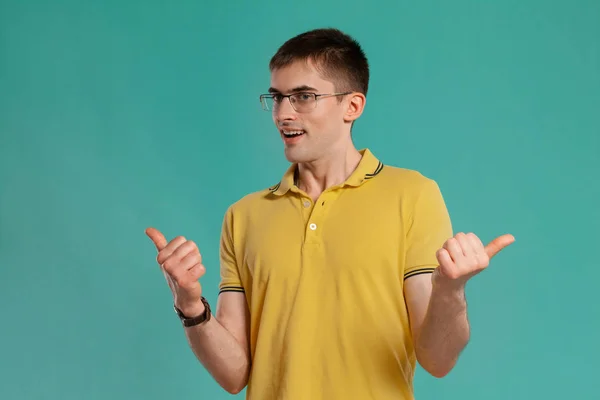 Chico guapo con una camiseta casual amarilla posando sobre un fondo azul . —  Fotos de Stock