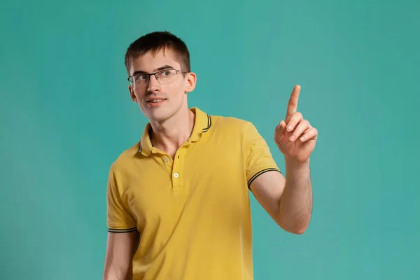 Stilig kille i en gul casual t-shirt poserar över en blå bakgrund. — Stockfoto