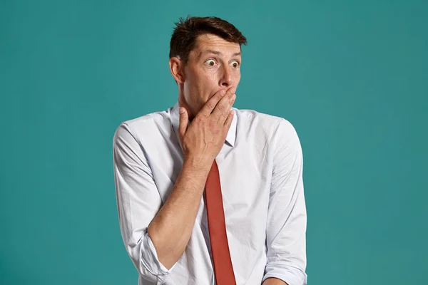 Hombre joven con una camisa blanca clásica y corbata roja posando sobre un fondo azul . —  Fotos de Stock