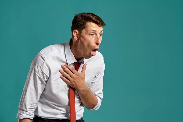 Junger Mann in klassisch weißem Hemd und roter Krawatte posiert vor blauem Hintergrund. — Stockfoto