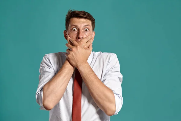 Young man in a classic white shirt and red tie posing over a blue background.