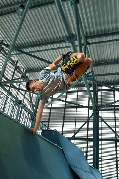 Rollerblader hoppa högt från Big Air ramp utför trick. Inomhus skate park utrustning. — Stockfoto