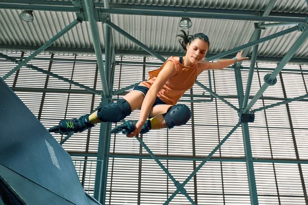 Rollerblader sauter haut de la grande rampe d'air performant tour. Équipement de skate park intérieur . — Photo