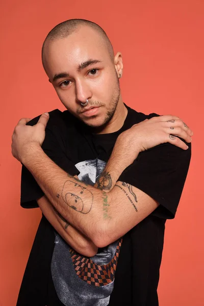 Foto de estudio de un joven calvo tatuado posando sobre un fondo rosa. Estilo de los años 90 . — Foto de Stock