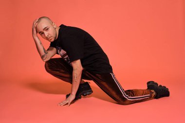 Pembe bir arka plan aleyhine poz veren genç, dövmeli kel bir adamın stüdyo fotoğrafı. 90'ların stili.