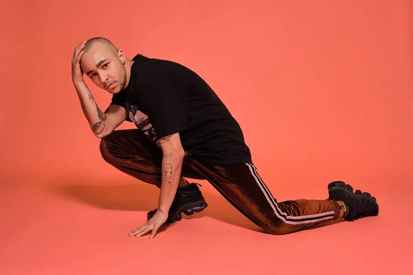 Foto de estudio de un joven calvo tatuado posando sobre un fondo rosa. Estilo de los años 90 . — Foto de Stock