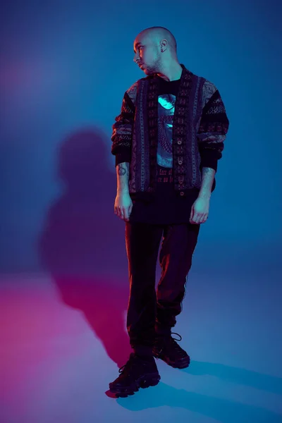 Captura de estudio de un joven calvo tatuado posando sobre un fondo colorido. Estilo de los años 90 . — Foto de Stock