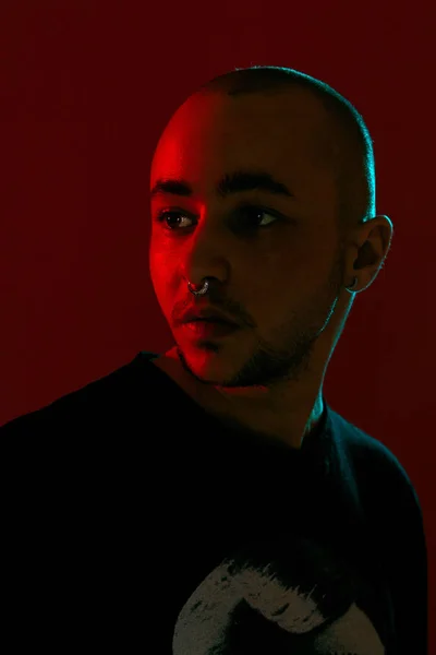 Fotografía de un joven calvo tatuado posando sobre un fondo rojo. Estilo de los años 90 . — Foto de Stock