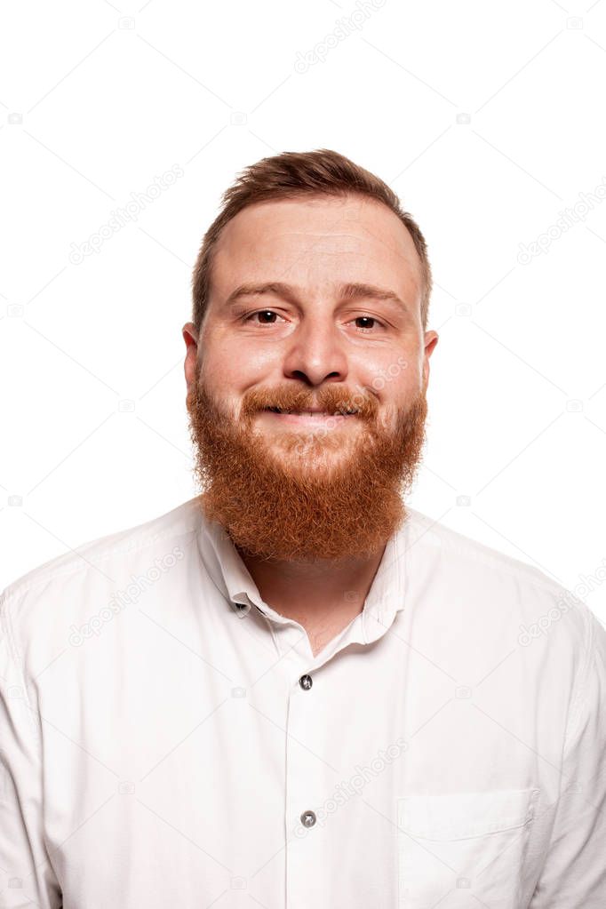 Portrait of a young, chubby, redheaded man in a white shirt making faces at the camera, isolated on a white background