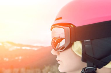 Kayak merkezinde kask ve dağların yansıması ile gözlük giyen snowboardcu kadının yakın portresi. Güneş parlaması