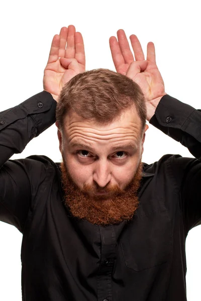 Portrait d'un jeune homme roux, potelé, vêtu d'une chemise noire faisant des grimaces à la caméra, isolé sur fond blanc — Photo