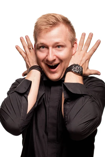 Young blond man in a black shirt, watches and bracelet is making faces, isolated on a white background — Stock Photo, Image