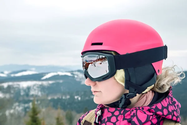 Portrait rapproché d'une snowboarder de la station de ski portant un casque et des lunettes reflétant les montagnes . — Photo