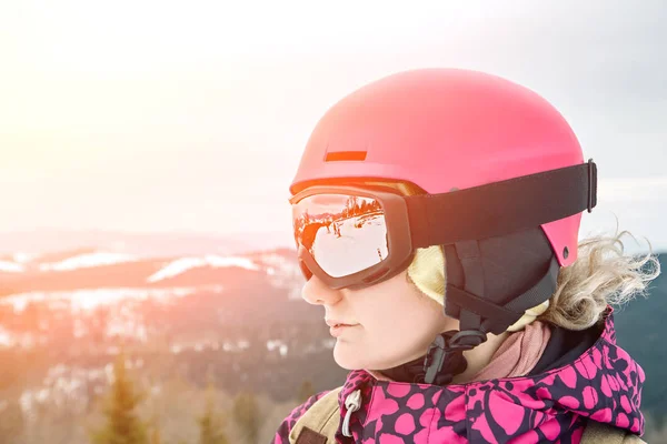 Retrato de cerca de la mujer snowboarder en la estación de esquí con casco y gafas con reflejo de las montañas. Bengala solar — Foto de Stock