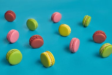 Renkli badem kurabiyesi ya da badem kurabiyesi, mavi arka planda tatlı kremalı şekerleme. Yakın plan, kopyalama alanı.