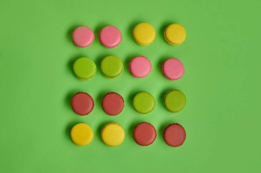 Renkli badem kurabiyesi ya da badem kurabiyesi, yeşil arka planda tatlı kremalı şekerleme. Yakın plan, kopyalama alanı.