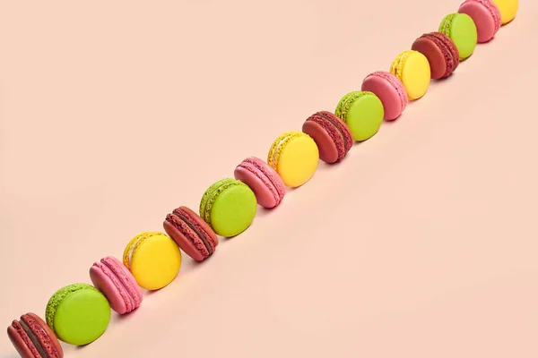 Gekleurde macaron of macaroon, zoete meringue-gebak op roze achtergrond. Close-up, kopieerruimte. — Stockfoto