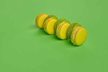 Renkli badem kurabiyesi ya da badem kurabiyesi, yeşil arka planda tatlı kremalı şekerleme. Yakın plan, kopyalama alanı.