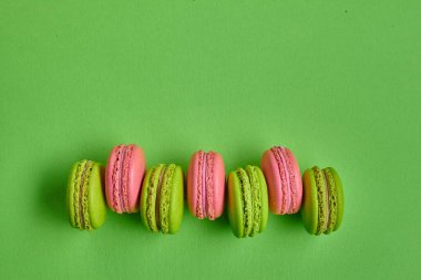 Renkli badem kurabiyesi ya da badem kurabiyesi, yeşil arka planda tatlı kremalı şekerleme. Yakın plan, kopyalama alanı.