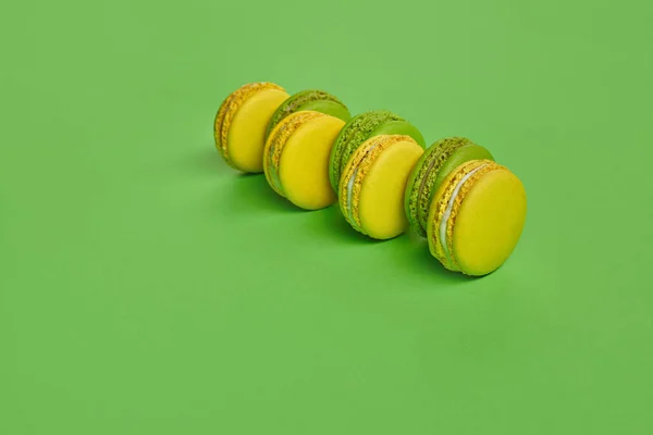 Camarón coloreado o macarón, dulces dulces a base de meringue en fondo verde. Cierre y copia del espacio. —  Fotos de Stock