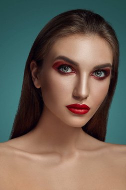 Gri bir arkaplan üzerinde parlak makyajlı, güzel, yarı çıplak bir mankenin göz kamaştırıcı portresi..
