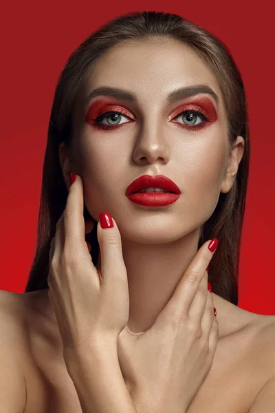Közelkép glamour portré egy gyönyörű félmeztelen modell fényes smink pózol egy piros háttér. — Stock Fotó